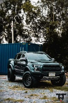 a black truck parked in front of a blue container