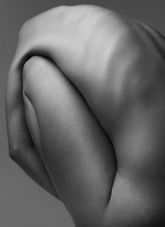 the back of a nude woman's head with her hands on her hips, looking down