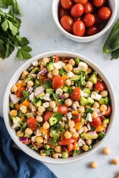 a white bowl filled with chickpea salad next to a blue napkin and tomatoes