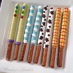 a white plate topped with lots of different types of candy sticks covered in icing