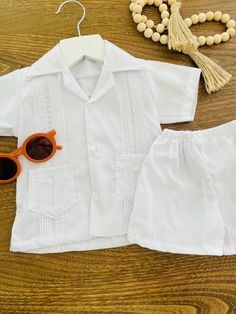 A summer version of a classic guayabera. These 2 piece baby white guayabera set is great for the summer events. A perfect blend of elegance and comfort, set includes 1 traditional shirt and 1 matching short with an elastic waist to keep your baby happy :) and for easy diaper changes.  Perfect for photo shoots, baptisms, weddings or any special events. -Hand-Made -Free Domestic Standard Shipping within the Us -Free Gift Wrap -Sizes Available from 3months - 2T https://www.etsy.com/listing/1526217110/spanish-white-boy-guayabera-set-perfect For Blue set click here; https://www.etsy.com/listing/1262927020/boy-guayabera-set-in-baby-blue-or-white For more handmade unique items check out our shop: https://www.etsy.com/shop/FredandAliBoutique message me for Rush order Baby Boy Clothing Sets, Shirt And Shorts, Beach Weddings, Summer Events, Clothing Sets, White Boys, Style Shirt, Boys Clothing, Baby Boy Outfits