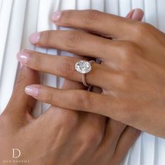 a woman's hand with a diamond ring on her left hand and a white background