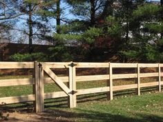 a wooden fence in the middle of a grassy field