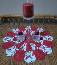 a table with two candles on it next to a wine glass and napkins that have been placed on the table