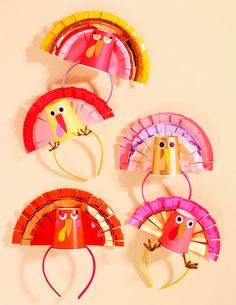 three paper turkeys are hanging on the wall and one has a headband around it