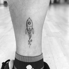 a black and white photo of a person's foot with a rocket ship tattoo on it