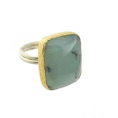 Chalcedony Ring Size 7 The beauty of the gemstone shines through in this polished chalcedony stone ring. Set in .925 sterling silver and 24K gold vermeil this ring will make a statement. Measures approximately 1" long and 0.75" wide. .925 Sterling silver 24K Gold vermeil Chalcedony semi-precious stone Size 7- may be sized Modern Chalcedony Rings For Gift, Green Chalcedony Gemstone Rings, Elegant Chalcedony Rings With Natural Stones, Gift Ring With Large Chrysoprase Stone, Handmade Elegant Chrysoprase Ring, Classic Chalcedony Ring Jewelry, Elegant Chalcedony Ring With Large Stone, Yellow Gold Chalcedony Jewelry With Cabochon, Formal Handmade Chalcedony Rings