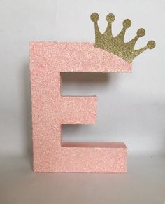 the letter e has a gold crown on it's top and is painted pink