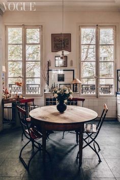 a dining room table and chairs in front of two windows