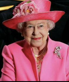 an older woman wearing a pink hat with flowers on the side and a rose brooch