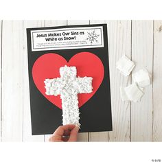 someone is holding up a cross made out of marshmallows on top of a card