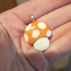 a hand holding a small orange and white mushroom pendant with words thanks for saving me from a landfill