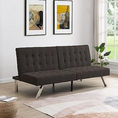 a black futon sofa sitting on top of a wooden floor next to a window