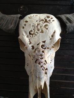 an animal skull with long horns and intricate carvings on it's back end, in front of a black background