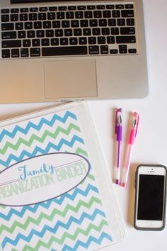 a personalized binder next to a laptop, cell phone and pen on a desk