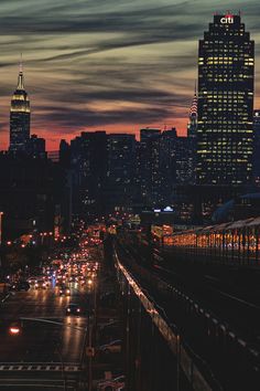 the city skyline is lit up at night, with cars driving on the street below