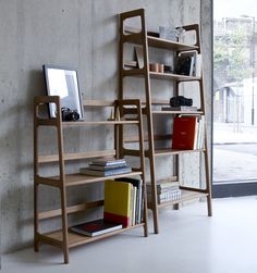 a book shelf with books on it next to a window and a wall in the background