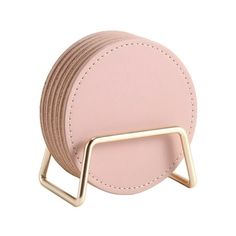 a pink round purse with a gold metal holder on the front and side, sitting on top of a white background