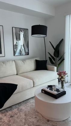 a living room with white couches and pictures on the wall above them, along with a coffee table