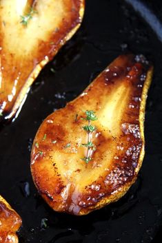 three pieces of food cooking in a skillet with sauce and herbs on top,