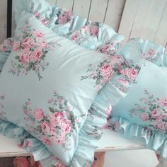 three pillows on a bench with pink flowers and ruffles around the pillowcase