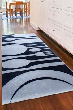 an area rug in the middle of a kitchen with white cabinets and wooden flooring