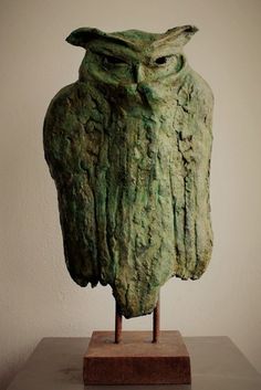 an owl statue sitting on top of a wooden stand