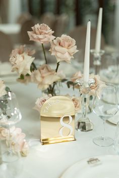 the table is set with pink roses and candles for an elegant wedding breakfast or reception