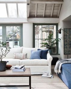 a living room with white couches and blue throw pillows on the back of it