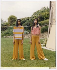 two young women standing next to each other in the grass