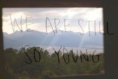 we are still so young written on a window sill with mountains in the background