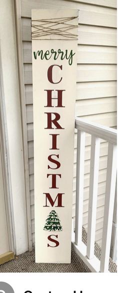 a christmas sign sitting on top of a porch next to a white house with the words merry christmas written on it