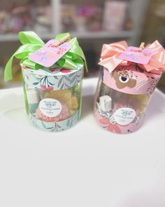 two jars with candy in them sitting on a table next to each other and one has a bow around the top