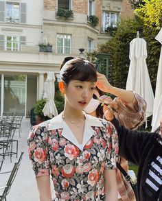 a woman is getting her hair styled by another woman in front of an apartment building