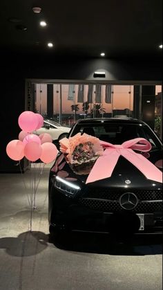 a black car with pink balloons tied to it