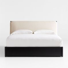 a bed with two pillows on top of it and a white wall in the background