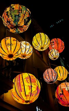 many colorful lanterns hanging from the side of a building