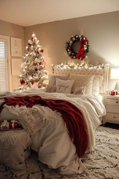 a bedroom decorated for christmas with white and red decorations on the bed, wreaths and lights