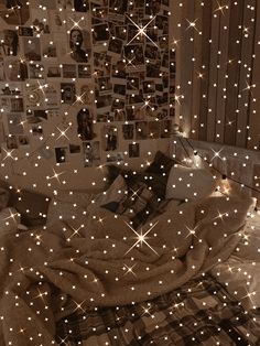 a bed covered in lots of white stars and lights next to a wall with pictures on it