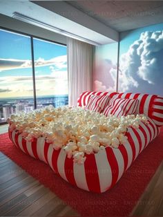 a large red and white striped couch with popcorn on it in front of a window