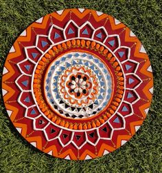 an orange and blue plate sitting on top of green grass