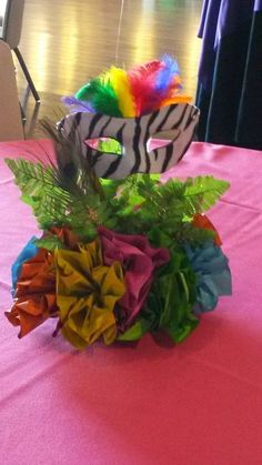 a zebra mask sitting on top of a table covered in flowers and leaves, next to a vase filled with feathers