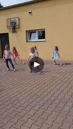 a group of children playing with a ball in front of a yellow bricked building