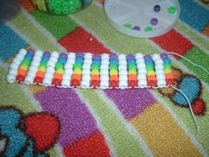 a rainbow colored plastic bead laying on top of a colorful blanket next to a toy