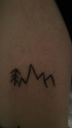 a tattoo on the back of a woman's shoulder with mountains and trees in it