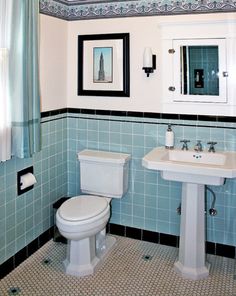 a white toilet sitting next to a sink in a bathroom under a mirror and framed pictures