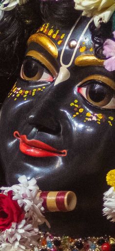 a close up of a mask with flowers on it's head and eyes painted black