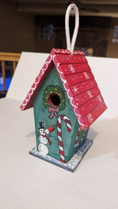 a birdhouse with a christmas decoration on it's roof and candy canes hanging from the top