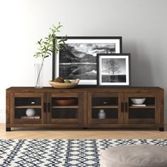 a wooden entertainment center with two pictures on the wall