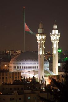 two tall white towers with lights on them in the middle of a city at night